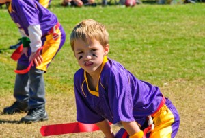 Child playing flag football but he is wearing a mouth guard to protect his teeth.